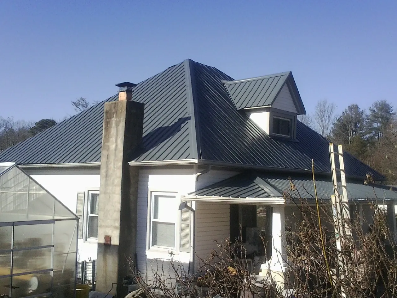 Dark blue standing seam metal roof on a white farmhouse with dormer — Slate & Tile Roof Repair by Roofing Brothers in Mount Gilead