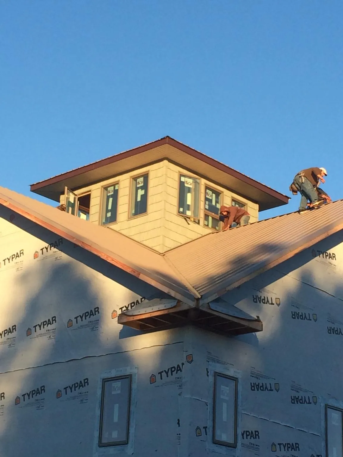 Roofers working around a rooftop cupola on a new metal roof at sunset — Roof Waterproofing in Mount Gilead by Roofing Brothers